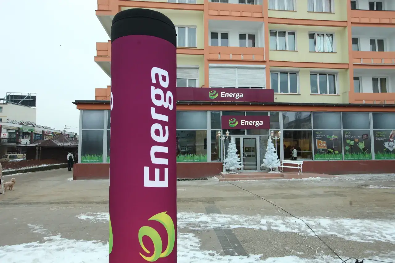 Duży, fioletowy słup z logo Energa przed budynkiem salonu sprzedaży.
