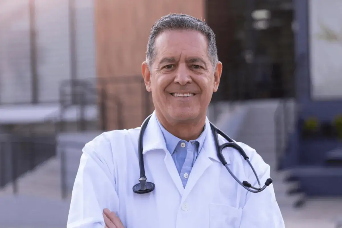 Uśmiechnięty lekarz w białym kitlu ze stetoskopem. Zastanawiasz się, ile zarabia lekarz rezydent?