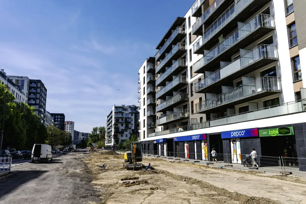 Budowa osiedla, gdzie można sprawdzić, ile zarabia deweloper na bliźniaku. W tle nowoczesne bloki, na pierwszym planie plac budowy.