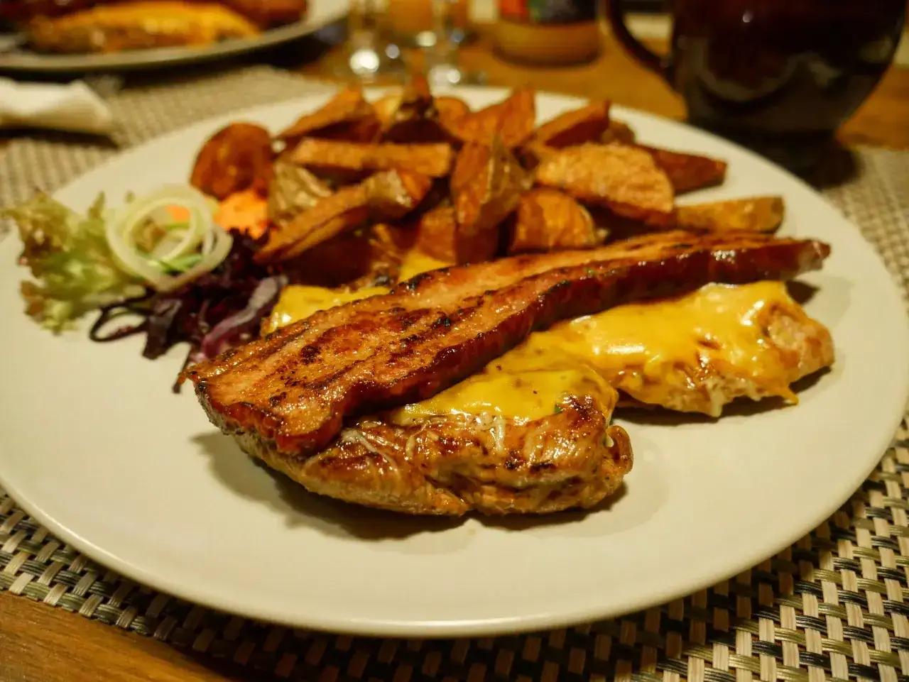 Pyszny burger z bekonem i serem, podany z frytkami i surówką. Smakuje jak w bacówce u Józka w Łodzi!