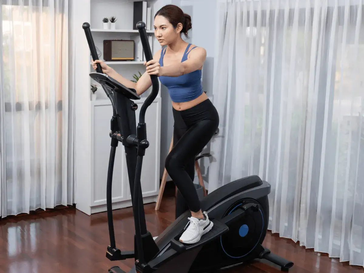 Kobieta ćwiczy na orbitreku, czerpiąc korzyści z treningu cardio.