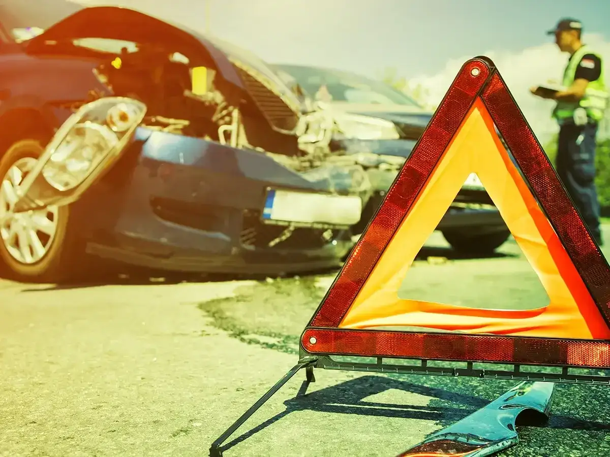 Trójkąt ostrzegawczy i uszkodzony samochód po wypadku. Na drodze widać też funkcjonariusza. To wyposażenie samochodu we Włoszech, które może uratować życie.