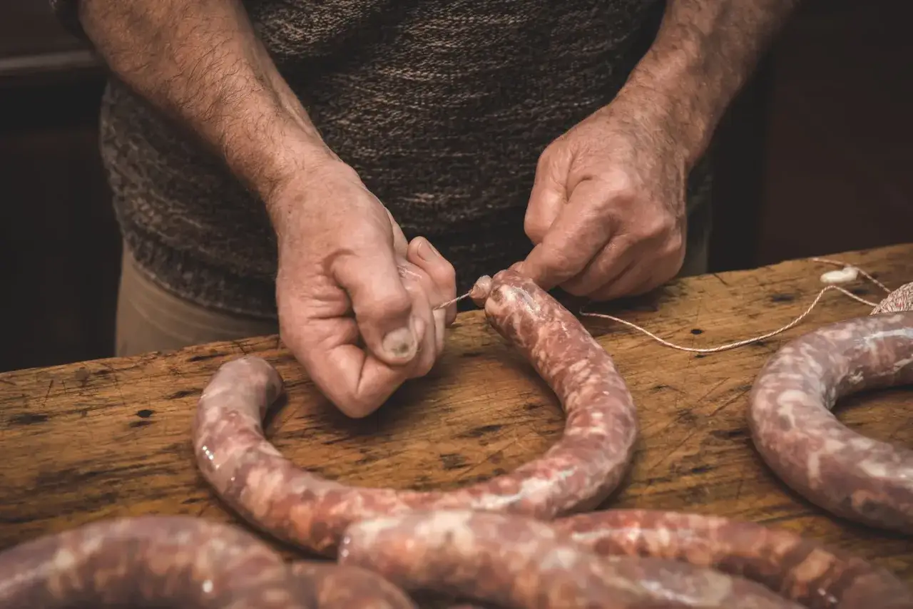 Ręce wiążą kiełbasę sznurkiem. Zastanawiasz się, jak długo wędzić kiełbasę bez parzenia?