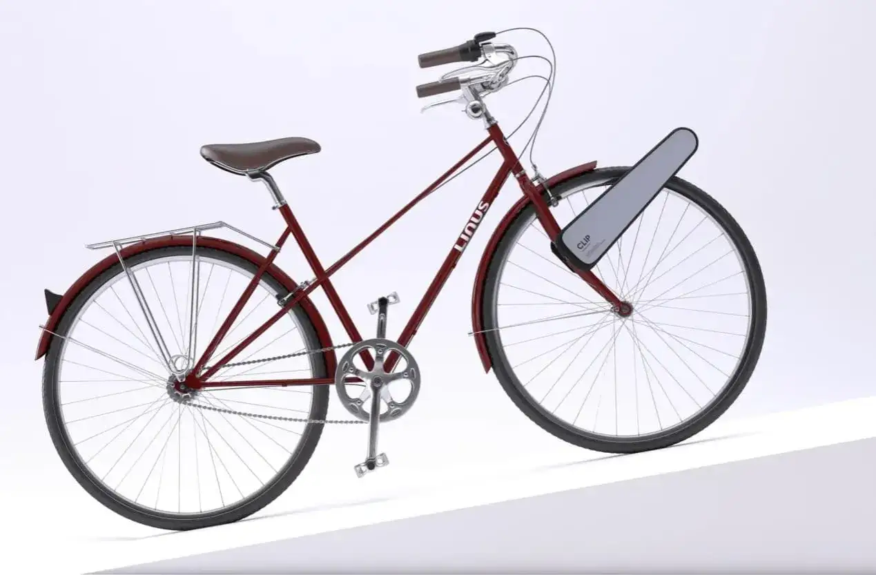 Czerwony rower miejski z brązowym siodełkiem i bagażnikiem. Na przednim kole zamontowany jest napęd elektryczny do roweru na przednie koło CLIP.