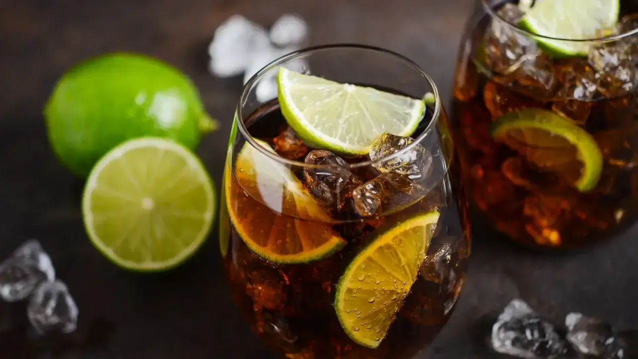 Orzeźwiający Cuba Libre z kostkami lodu i plasterkami limonki, gotowy do wypicia.