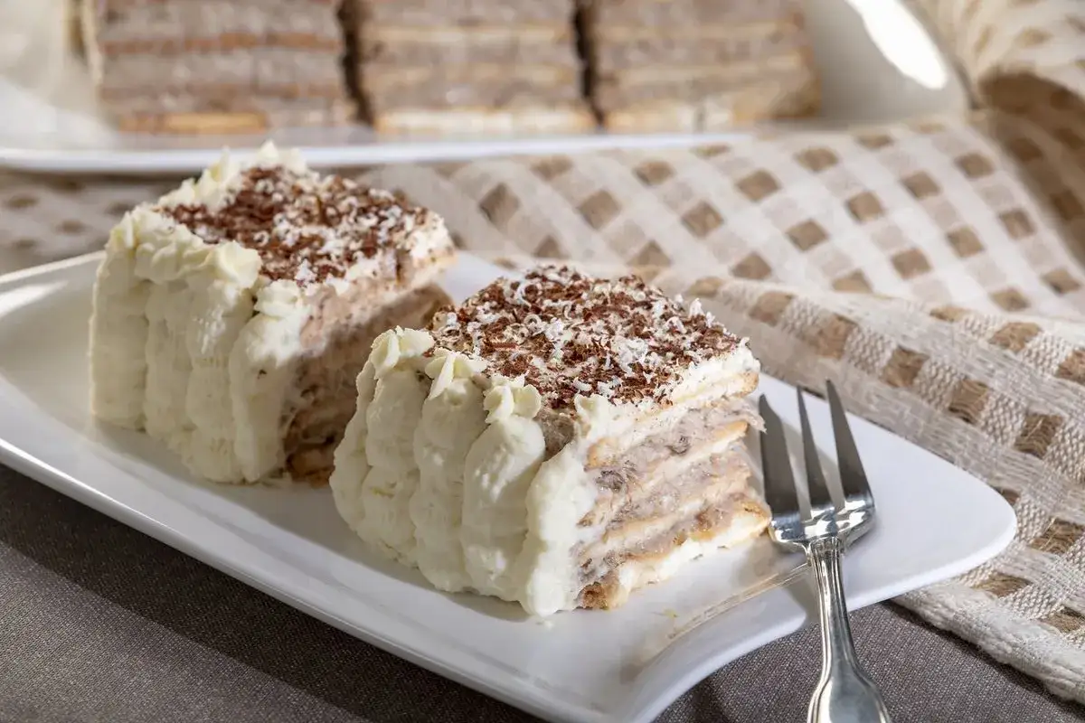 Dwa kawałki pysznego, warstwowego ciasta z kremem i posypką czekoladową. Idealne na tanie przepisy na ciasta i desery.