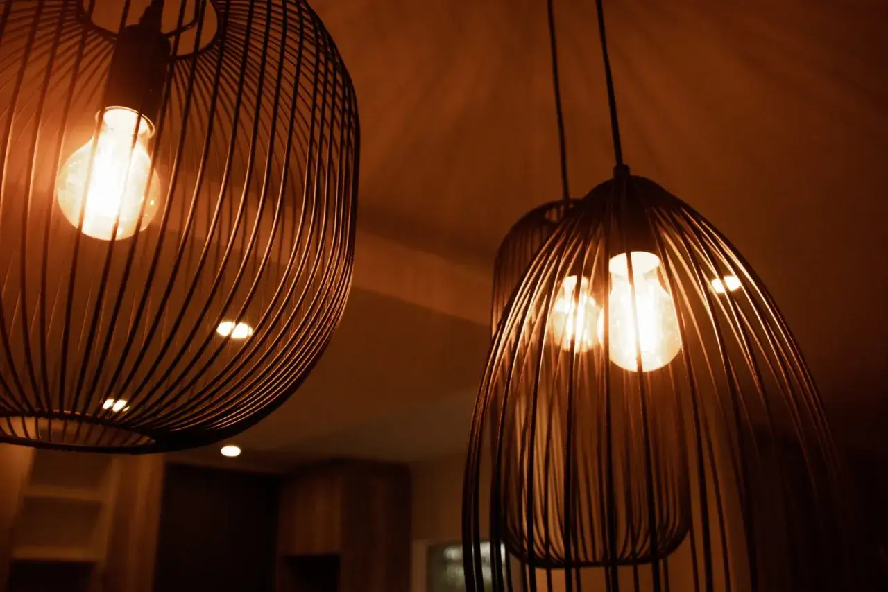 Trzy nowoczesne lampy wiszące z metalowymi kloszami i żarówkami Edisona.