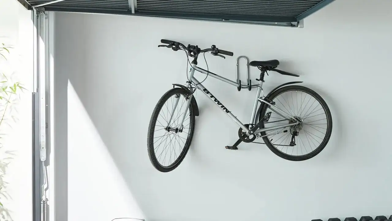 Srebrny rower zawieszony na ścianie, pokazujący, jak powiesić rower na ścianie, oszczędzając miejsce.