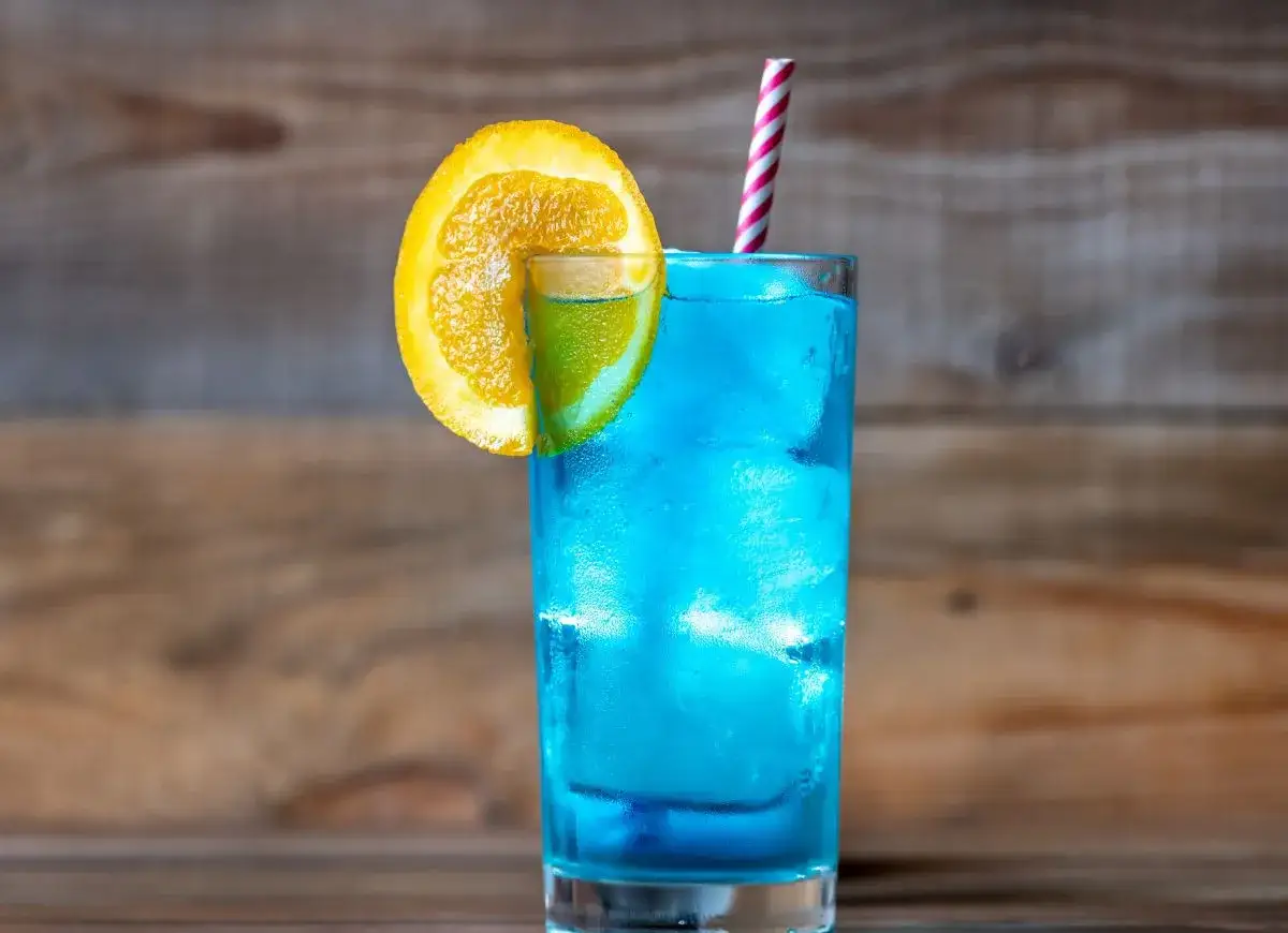 Orzeźwiający drink z blue curacao, ozdobiony plasterkiem pomarańczy i limonki, z kolorową słomką. Idealny na letnie popołudnie.