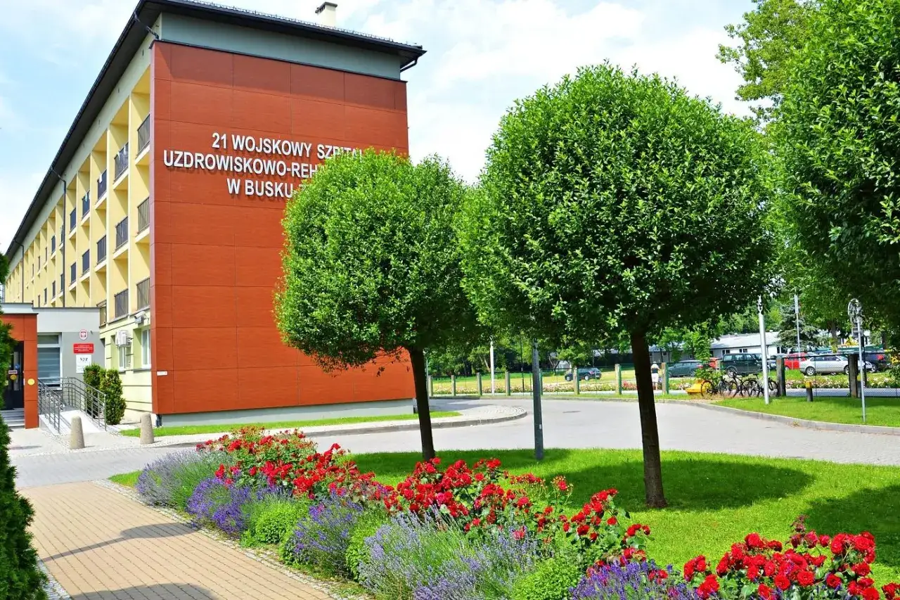 Sanatorium MSW Busko Zdrój z czerwonymi różami i lawendą w słoneczny dzień.