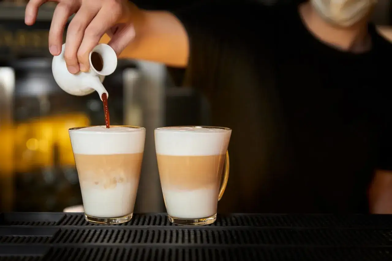 Barista wlewa espresso do dwóch latte macchiato. Zastanawiasz się, ile kcal ma latte macchiato?