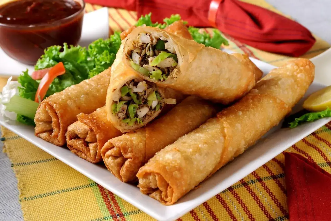 Chrupiące, złociste pieczone sajgonki z warzywnym farszem, podane z sosem i cytryną. Idealna przekąska.