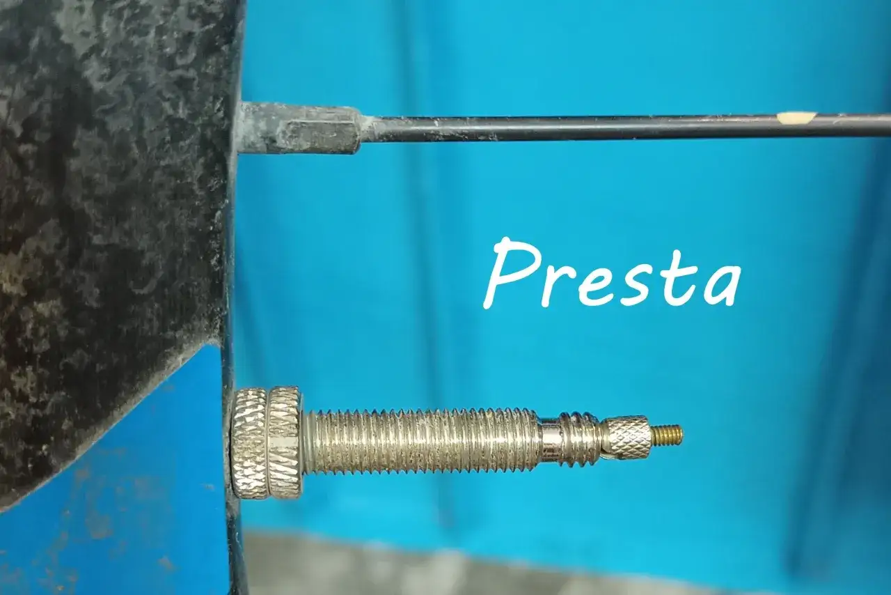 Szczegółowy widok wentyla Presta na kole rowerowym, gotowego do pompowania kompresorem.