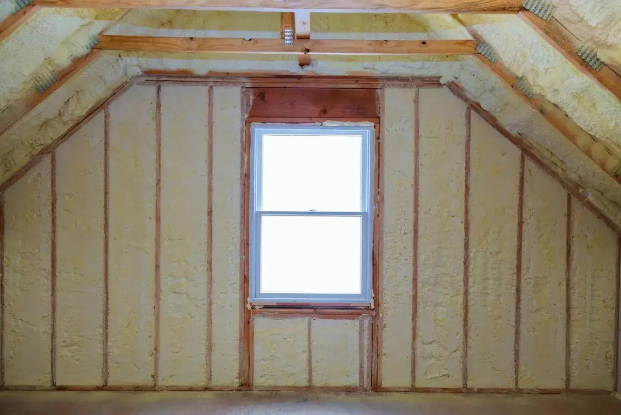 Ocieplony pianką poliuretanową dach skośny domu szkieletowego z oknem.