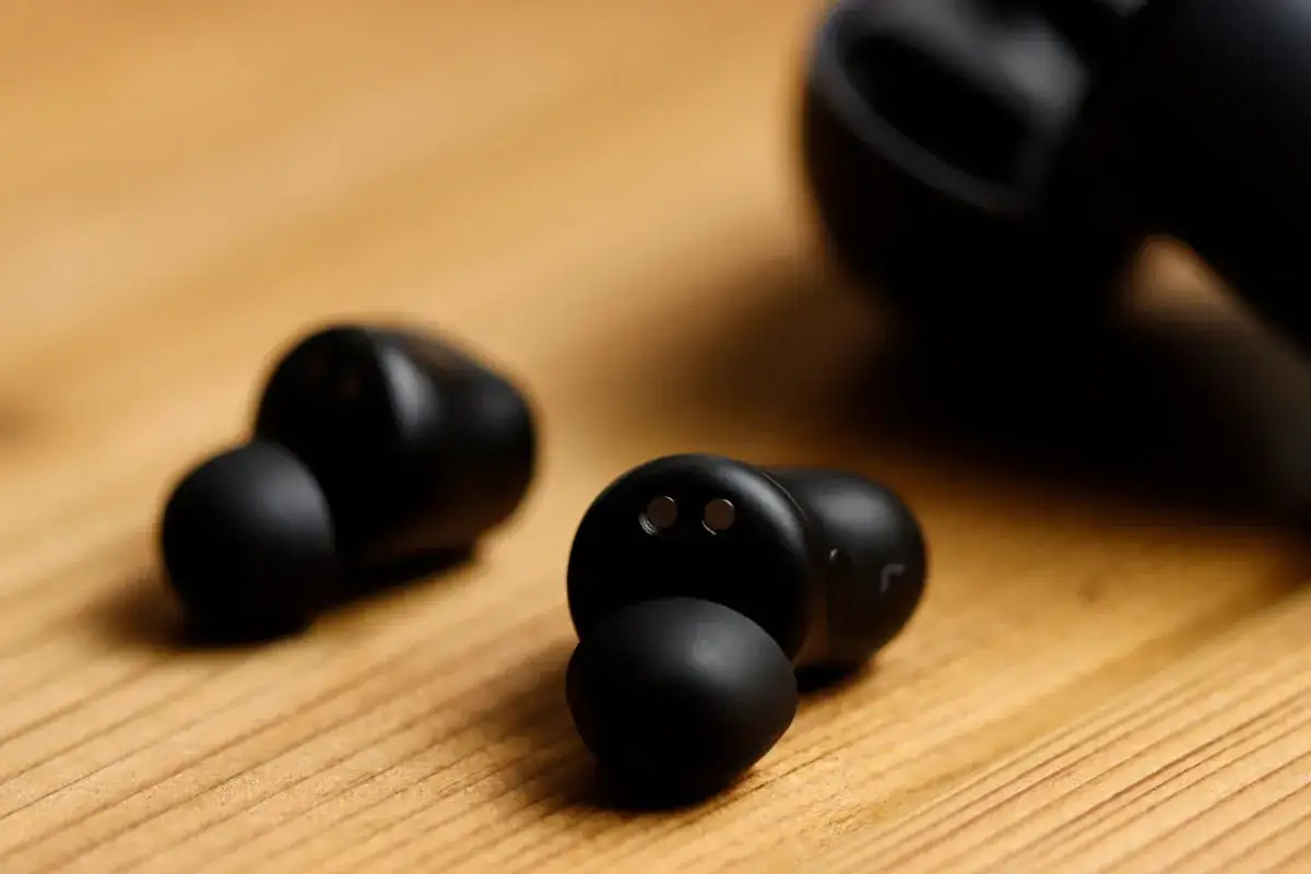 Czarne słuchawki dokanałowe na drewnianym tle. Dowiedz się, jak wyczyścić słuchawki dokanałowe, aby cieszyć się czystym dźwiękiem.