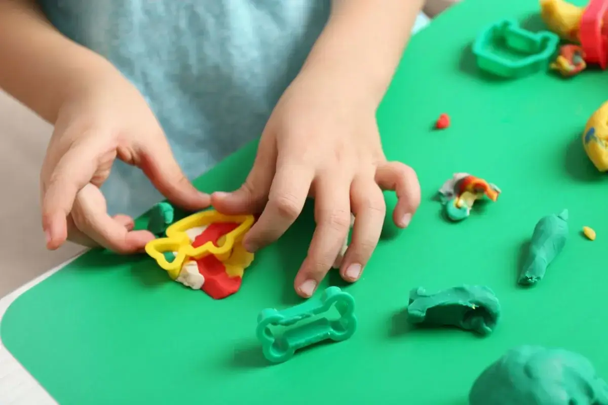 Dziecko bawi się kolorową modeliną i plasteliną, tworząc różne kształty.
