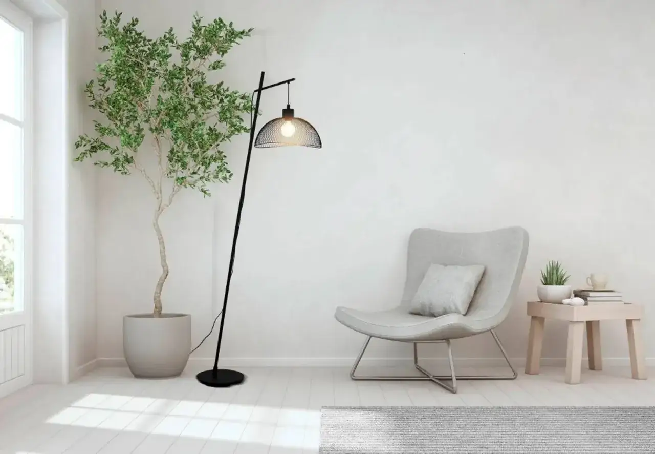 Nowoczesna, czarna stojąca lampa led z metalowym kloszem, oświetlająca przytulny kącik z fotelem i rośliną.