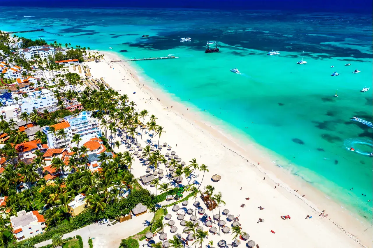 Rajskie plaże, palmy i turkusowe morze – idealne miejsce, kiedy na rejs po Karaibach. Widać hotele i łodzie.