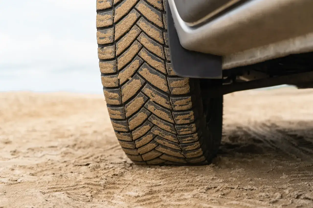 Opona samochodowa pokryta piaskiem na piaszczystym podłożu.