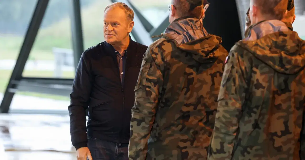 Donald Tusk rozmawia z żołnierzami w mundurach. Czy Donald Tusk był w wojsku? Nie ma informacji, by służył w armii.