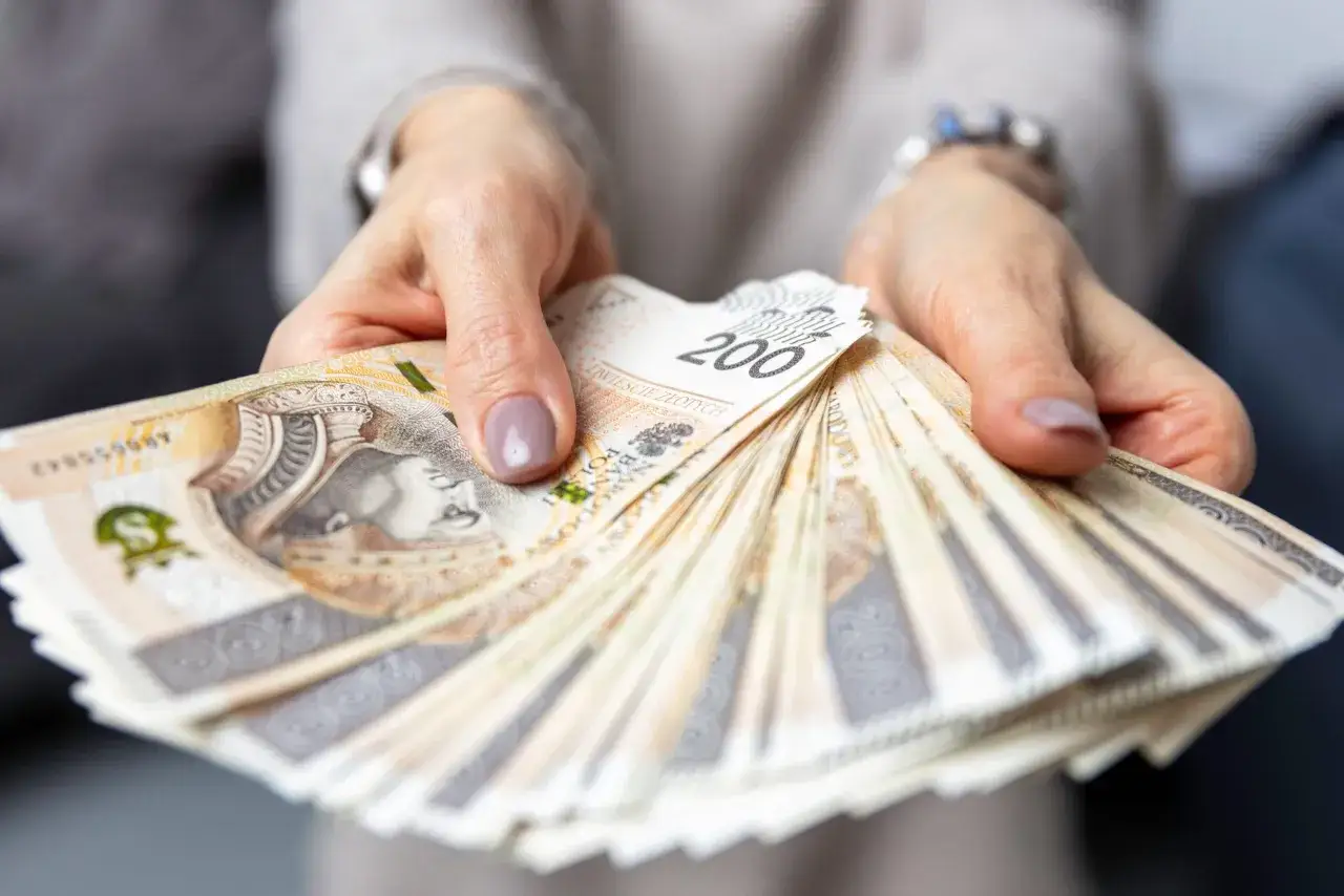 Dłonie trzymające wachlarz polskich banknotów 200 zł.