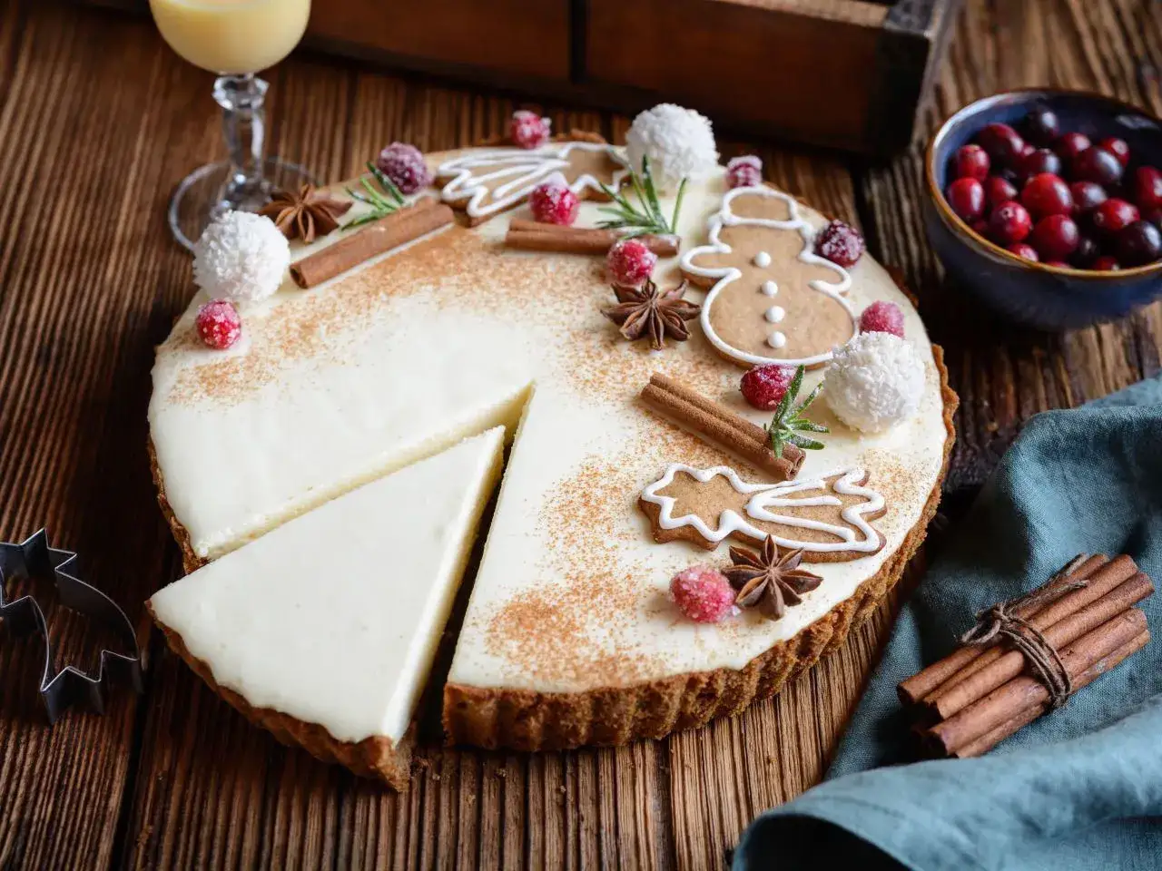Świąteczny sernik ozdobiony piernikami, laskami cynamonu i żurawiną. Idealny pomysł, jak ozdobić sernik na święta.
