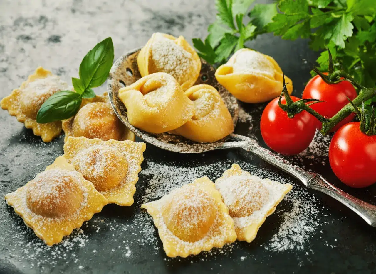 Świeże ravioli i tortellini, posypane cukrem pudrem, z pomidorkami koktajlowymi i bazylią. Idealne z czym podawać ravioli? Z prostym sosem!