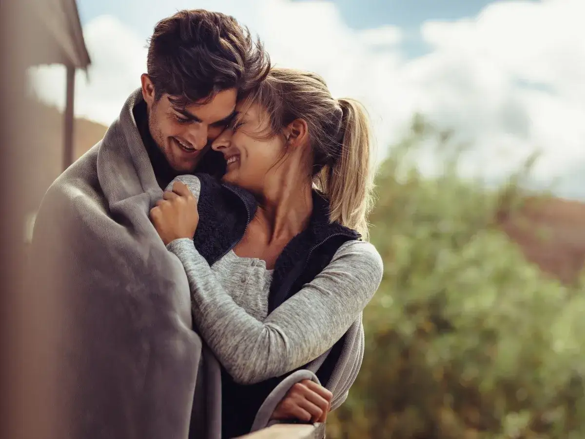 Para, kiedy mężczyzna kocha kobietę, przytuleni pod kocem, śmieją się.