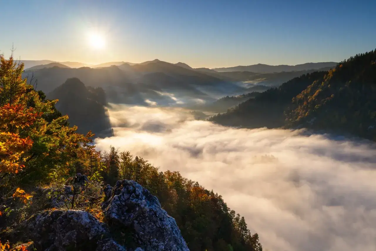 Poranek w górach, mgła spowija doliny. Idealne miejsce, by zastanowić się, jaki szlak wybrać w Tatrach. Słońce przebija się przez chmury, malując krajobraz.