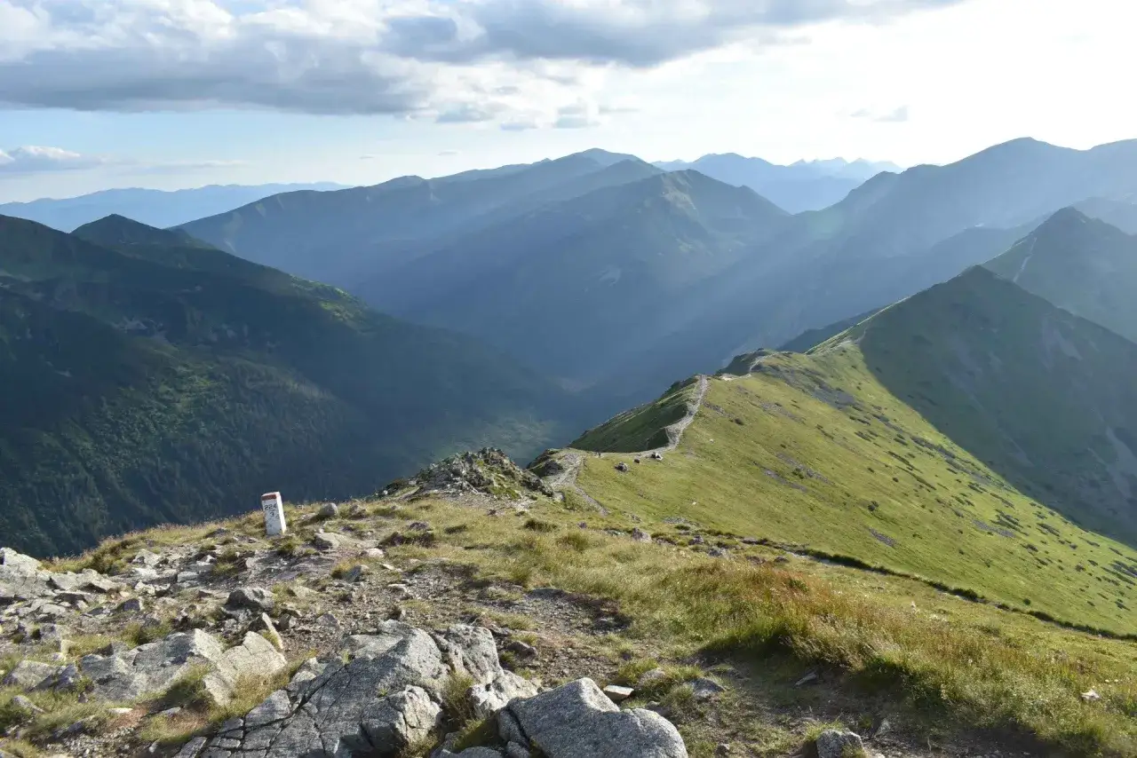 Widok na pasmo górskie Tatr z zielonymi zboczami i kamienistym szlakiem.