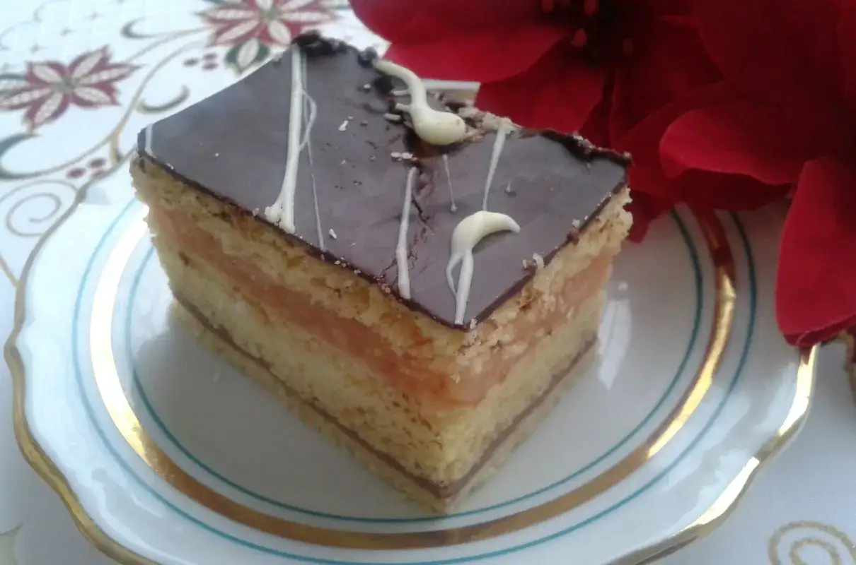 Pyszny kawałek ciasta z warstwami biszkoptu, kremu serowego i jabłek, oblany czekoladą. Idealny na przepis na ciasto delicja z serem i jabłkami.