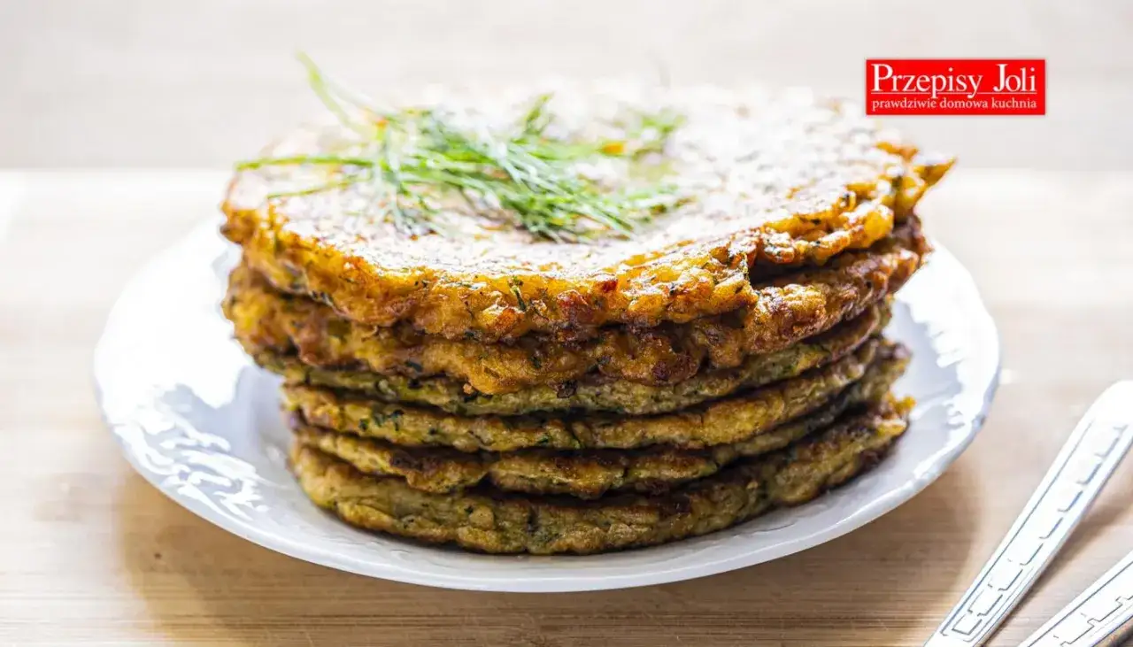 Stos placków z cukinii, idealnych jako dodatek do dania lub samodzielna przekąska. Ziołowy aromat i chrupiąca skórka zachęcają do spróbowania.