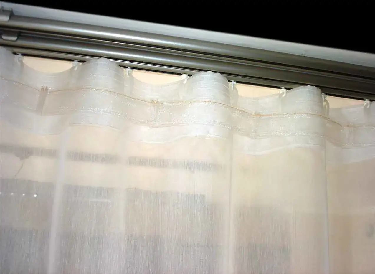 Biała, półprzezroczysta tkanina firanowa z wszytą taśmą marszczącą, która tworzy eleganckie fale. Różne rodzaje taśm marszczących pozwalają na uzyskanie odmiennych efektów.