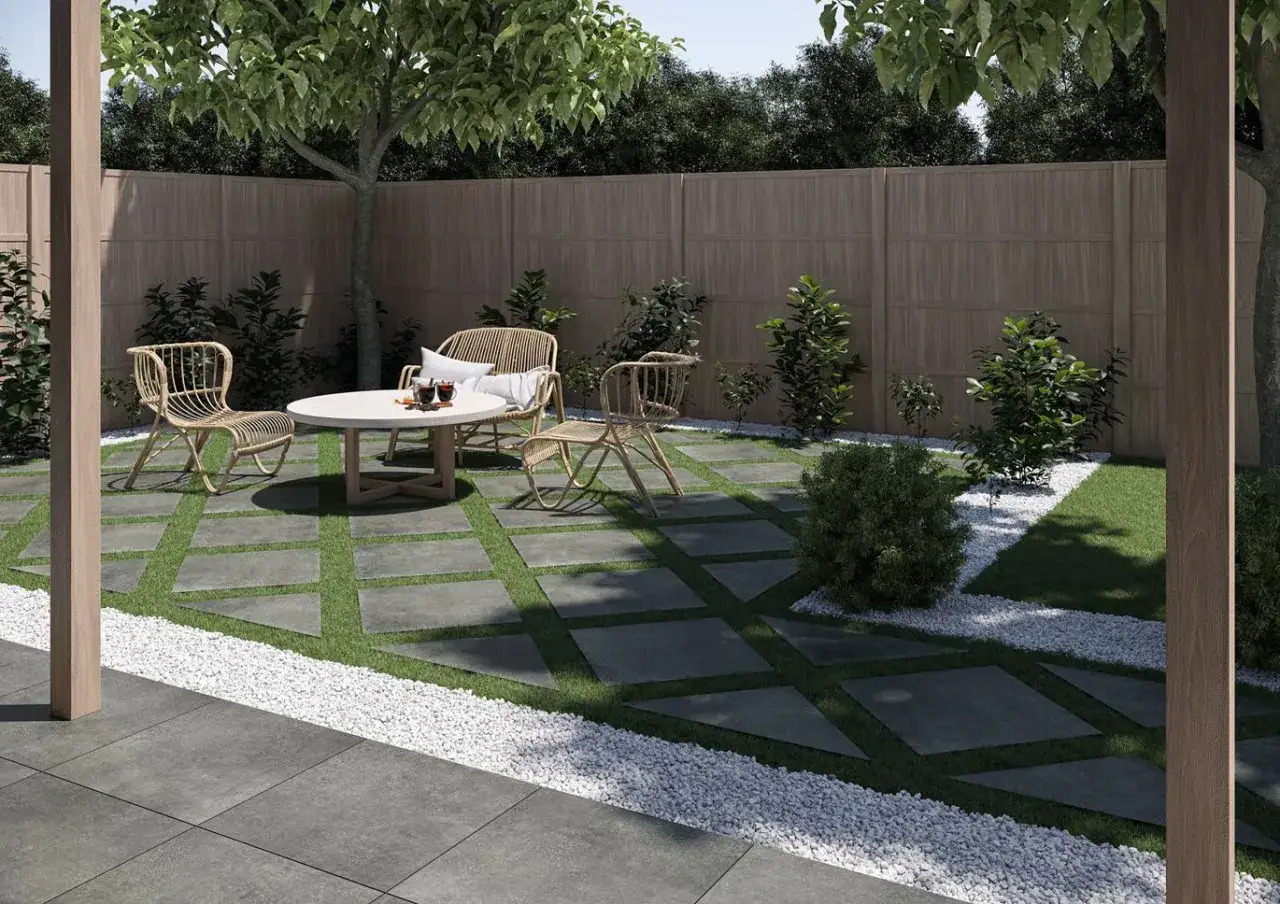 Nowoczesne ogrodzenie do ogrodu z drewnianym płotem i kamiennymi płytami na trawniku. Wygodny kącik wypoczynkowy z rattanowymi meblami.