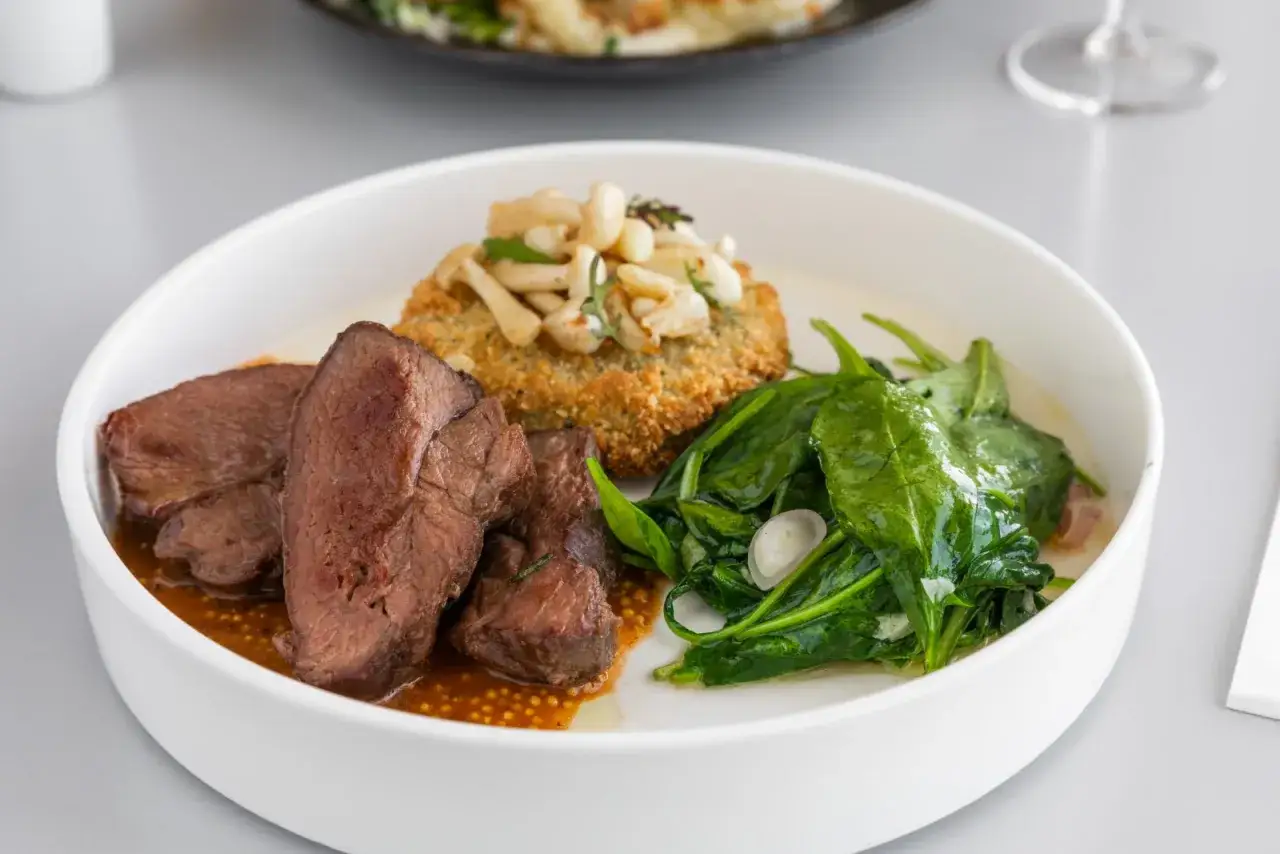 Wykwintne bukowina tatrzańska jedzenie: soczyste plastry wołowiny w sosie, panierowany kotlecik z grzybkami i świeży szpinak.