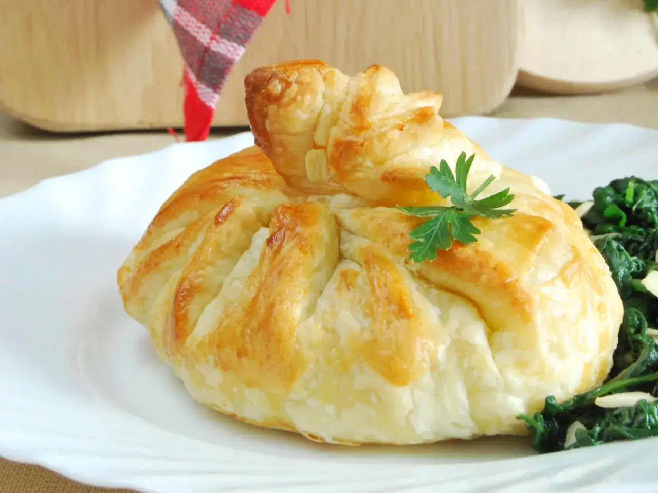 Złociste sakiewki z ciasta francuskiego, ozdobione natką pietruszki, podane z zielonymi warzywami.