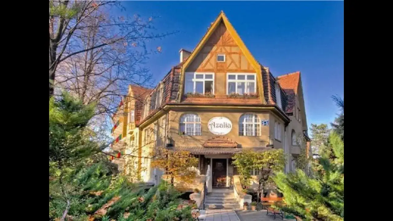 Sanatorium Azalia w Szczawnie-Zdroju, urokliwy budynek z charakterystycznym dachem i zielenią wokół.