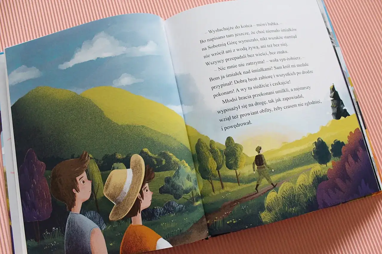 Dwóch chłopców patrzy na krajobraz, gdzie samotny podróżnik idzie ścieżką. To ilustracja z baśni o Sobotniej Górze.