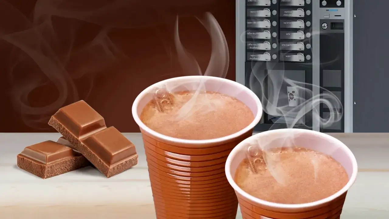 Ciepła czekolada z automatu, obok kostki czekolady. Zastanawiasz się, ile kcal ma czekolada z automatu?