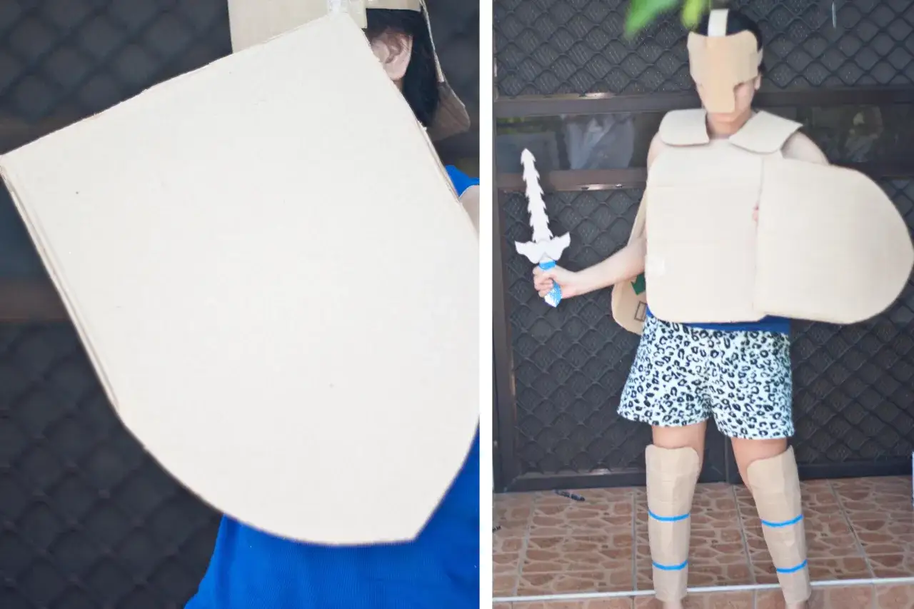 Osoba w zbroi z kartonu z tarczą i mieczem.