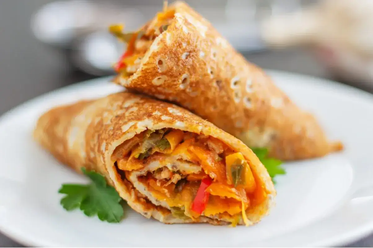 Dwa naleśniki z farszem warzywnym, idealne jako pomysł na obiad. Kolorowe warzywa i złocisty naleśnik kuszą.