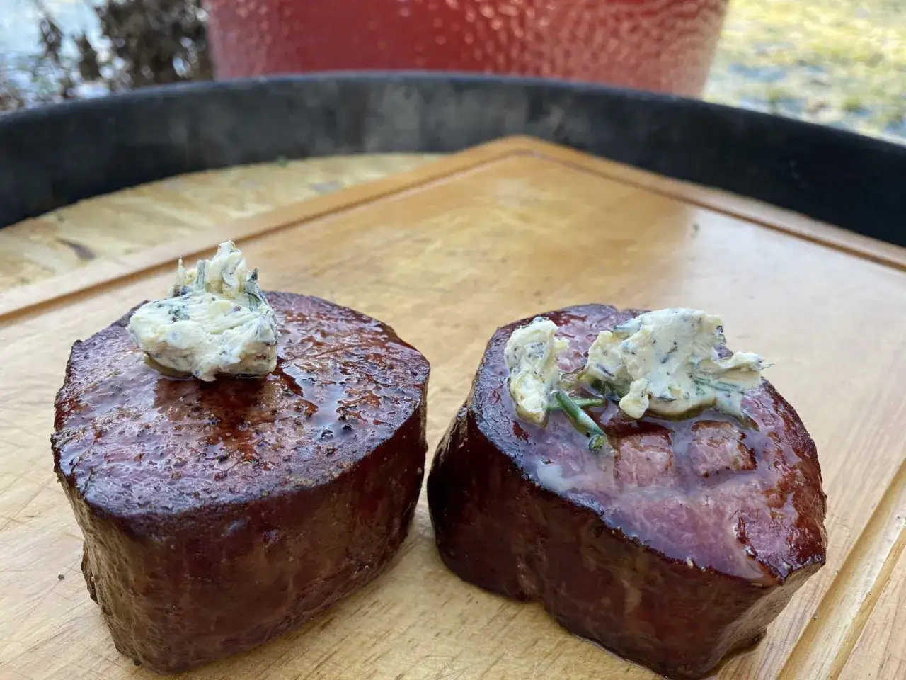 Dwa soczyste steki z polędwicy wołowej, polane masłem ziołowym, gotowe do podania.