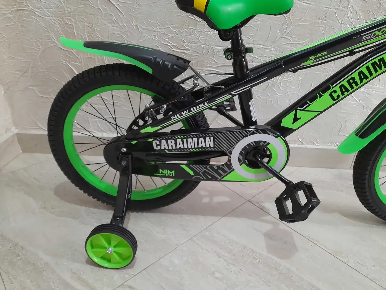 Czarny rower dziecięcy z zielonymi akcentami i napisem "CARAIMAN". To świetny rower dla początkujących.