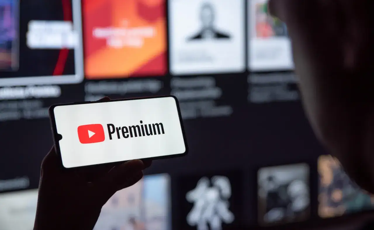 Telefon wyświetla logo YouTube Premium na tle ekranu z innymi treściami.