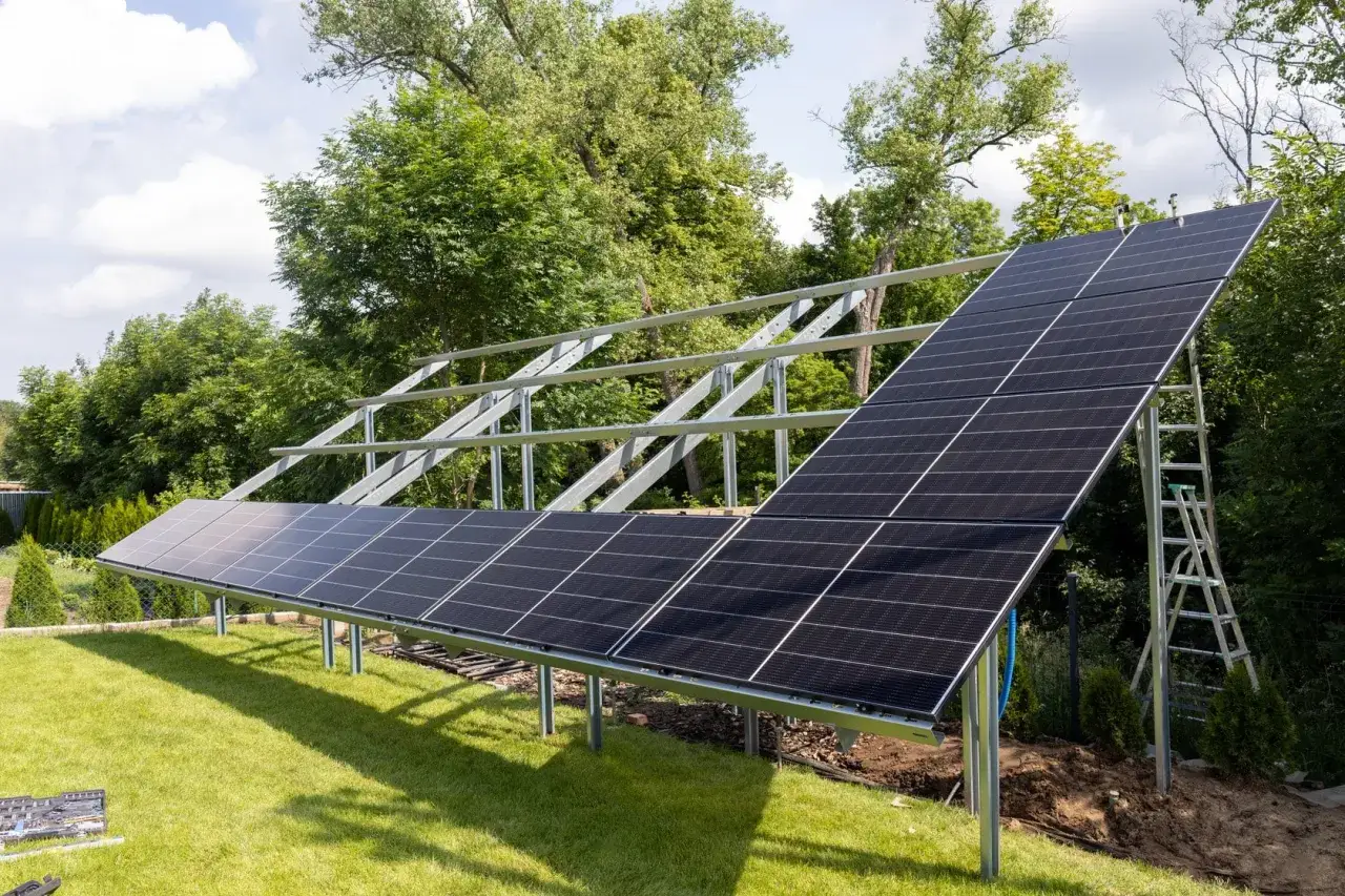 Instalacja PV co to? Panele słoneczne montowane na konstrukcji w ogrodzie, gotowe do produkcji czystej energii.