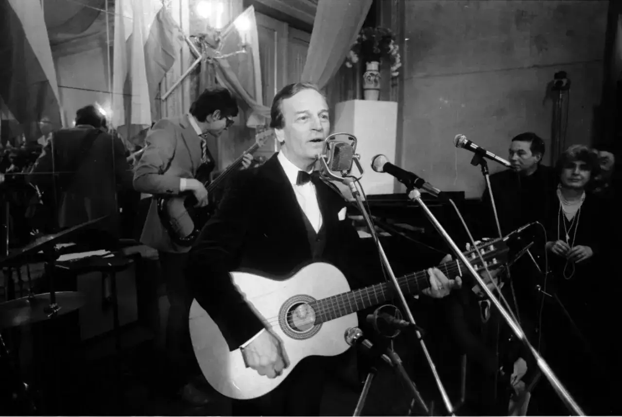 Zbigniew Kurtycz z gitarą i zespołem wykonuje swoje utwory. Wokalista w czarnym aksamitnym fraku śpiewa do mikrofonu.