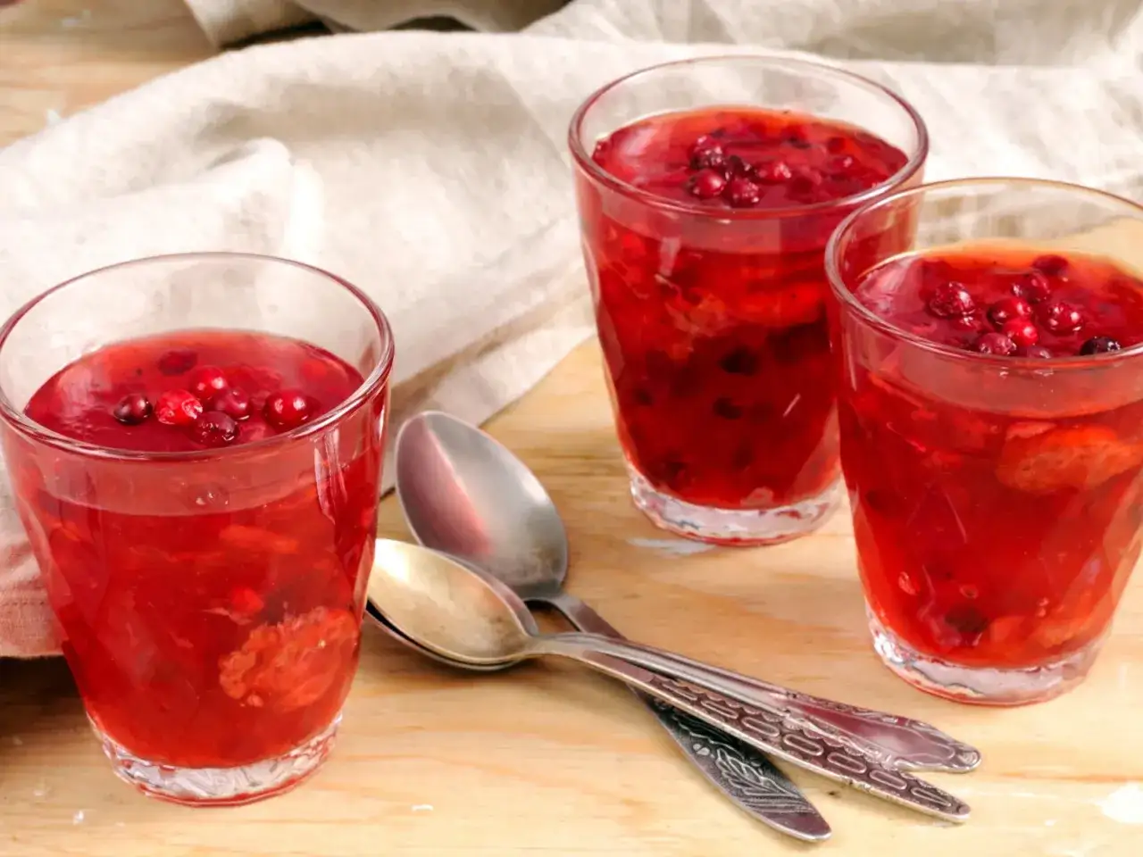 Trzy szklanki z czerwonym kisielem i owocami. Czy kisiel powoduje zaparcia? Ten deser wygląda pysznie!