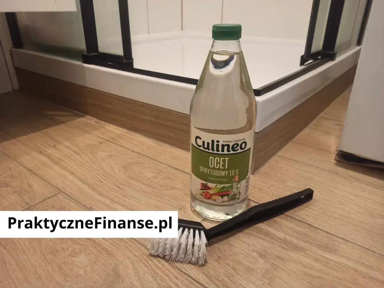 Butelka octu spirytusowego i szczotka do czyszczenia na drewnianej podłodze.