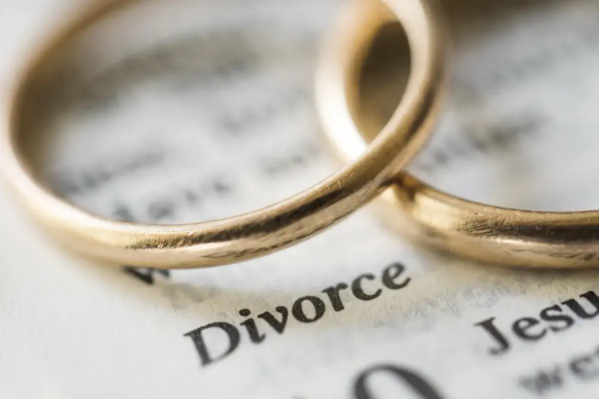 Dwa złote obrączki na kartce z napisem "Divorce".