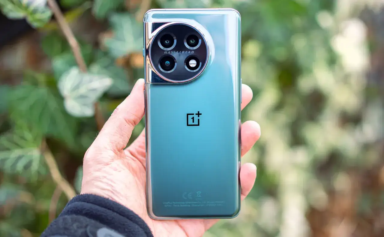 Dłoń trzyma zielony telefon z okrągłym aparatem Hasselblad.